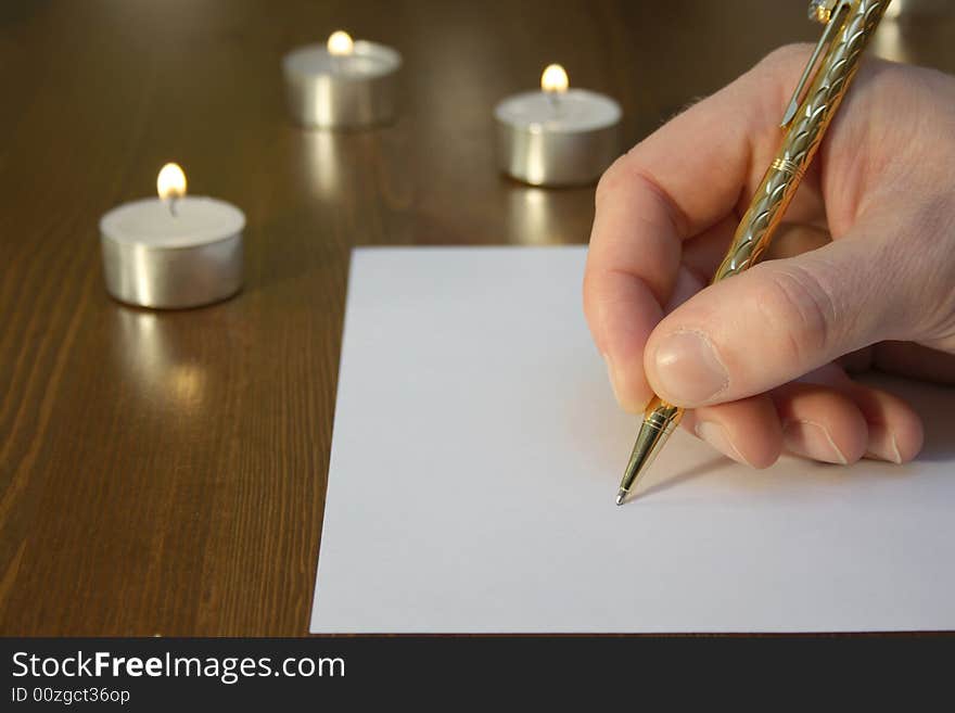 Hand wiriting with golden pen with candles. Hand wiriting with golden pen with candles