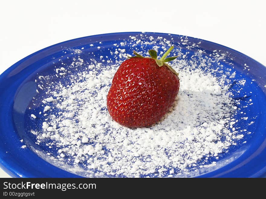 Single strawberry on blue plate with powdered sugar on white. Single strawberry on blue plate with powdered sugar on white