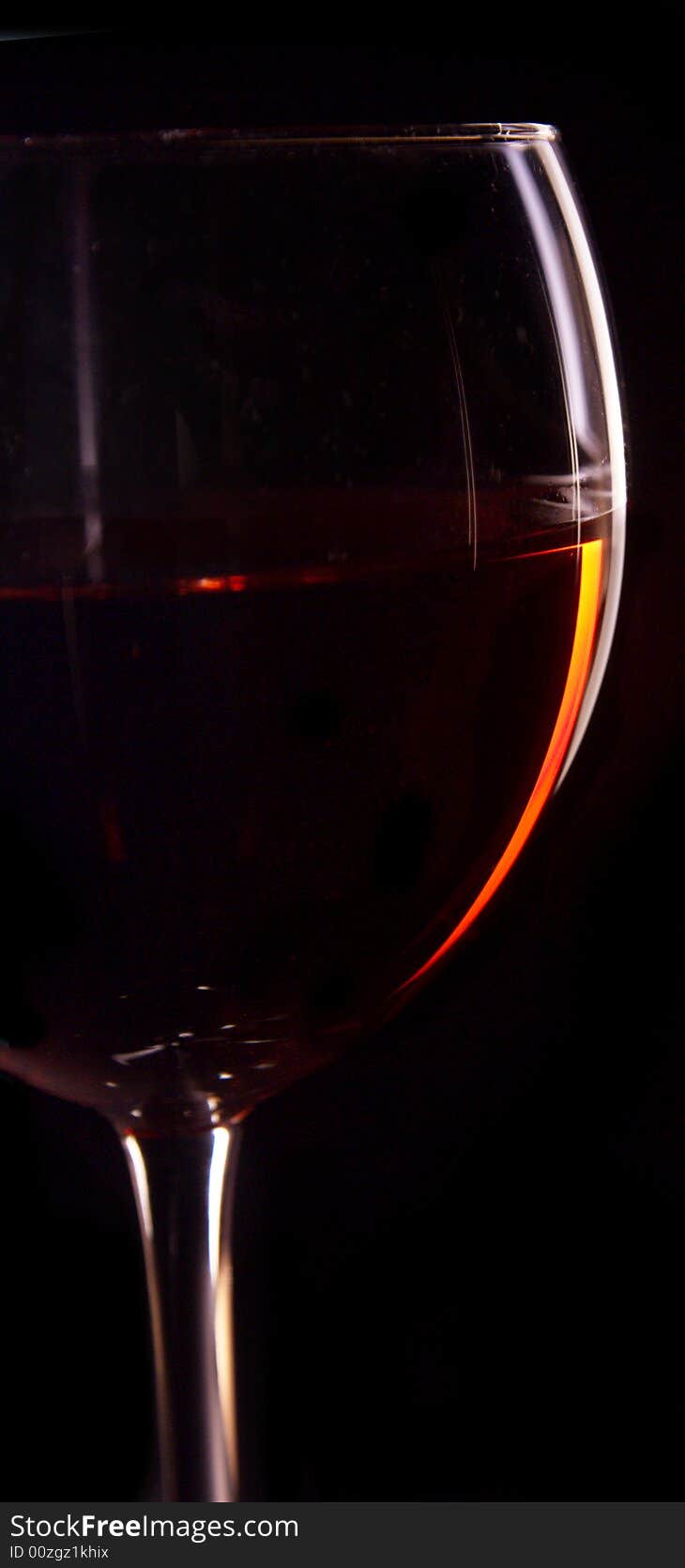 A wine glass with wine, lit to show just the edge of the glass to provide a clean, sleek composition. A wine glass with wine, lit to show just the edge of the glass to provide a clean, sleek composition.