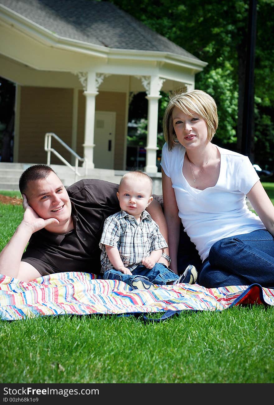 A happy family lying on a picnic mat on the grass. - vertically framed. A happy family lying on a picnic mat on the grass. - vertically framed