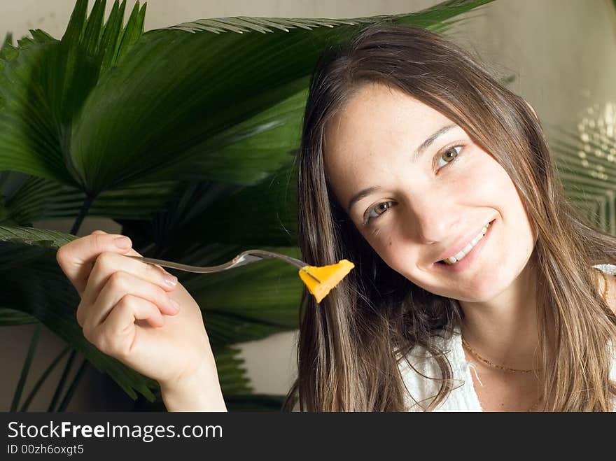 A young girl, in a white bathrobe eating a mango. - horizontally framed. A young girl, in a white bathrobe eating a mango. - horizontally framed