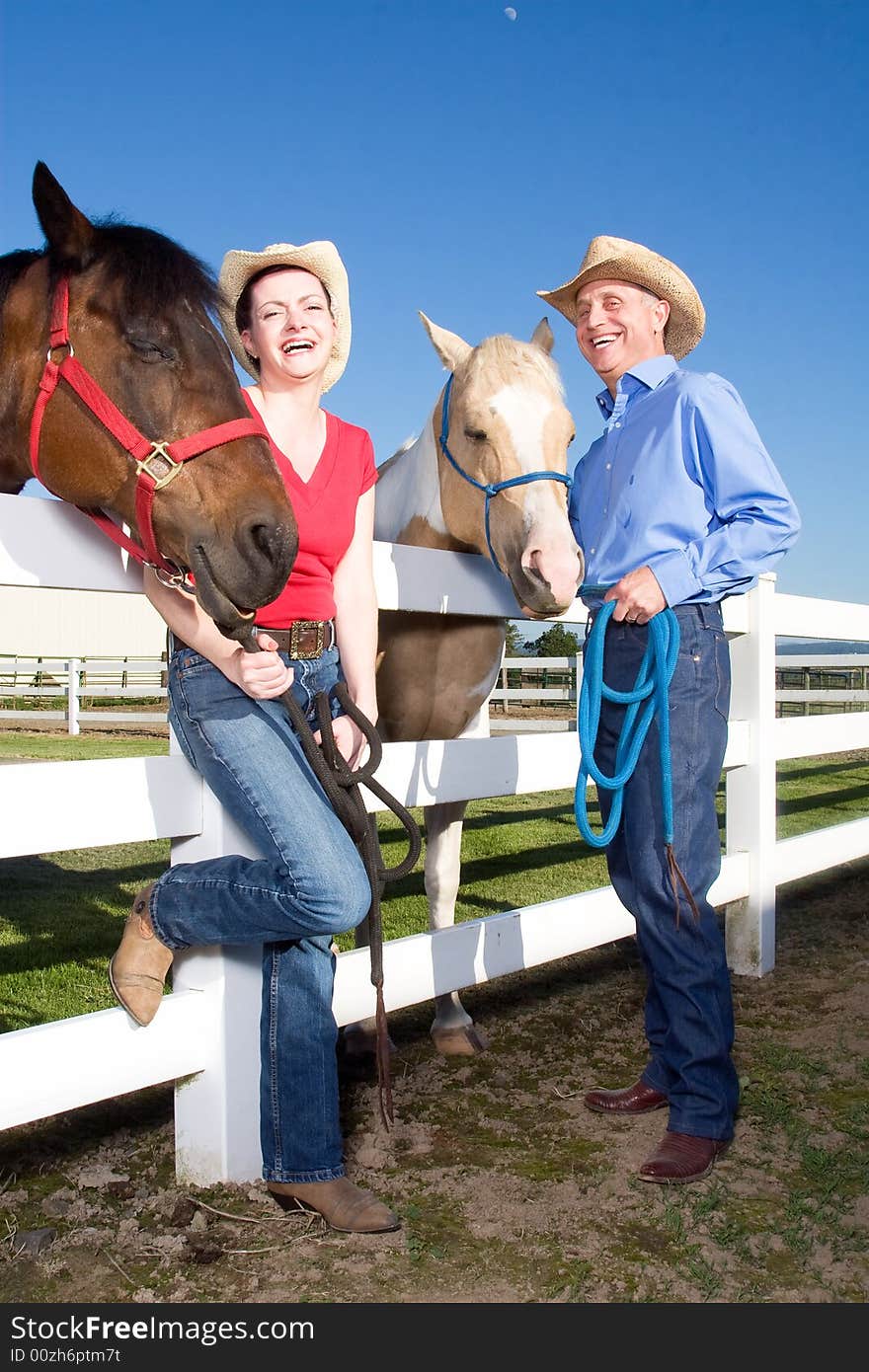 Two farmers happily standing, smiling, while holding their horses reigns. - vertically framed. Two farmers happily standing, smiling, while holding their horses reigns. - vertically framed