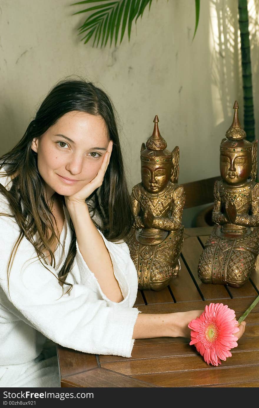 A Young girl smiling by two statues with a pink flower in her hand. - vertically framed. A Young girl smiling by two statues with a pink flower in her hand. - vertically framed