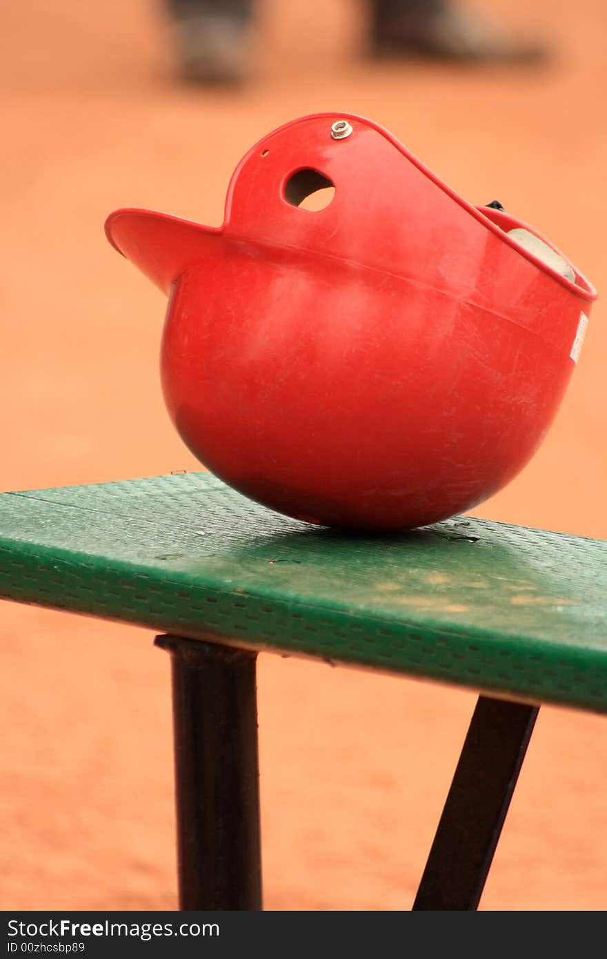 Still life of a red Baseball helmet sitting on a bench