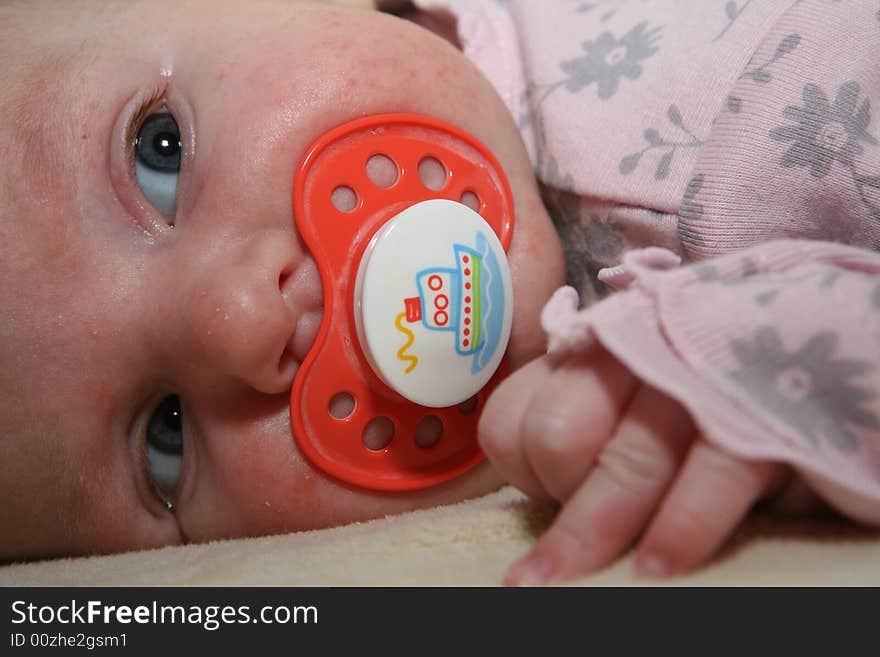 A new born baby with a pacifier in her mouth. A new born baby with a pacifier in her mouth