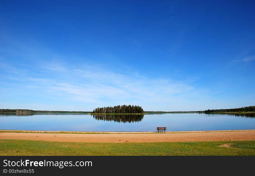 Island in the lake and a bench on the beach