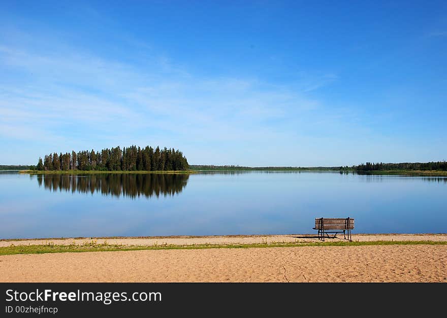 Island in the lake and a bench on the beach