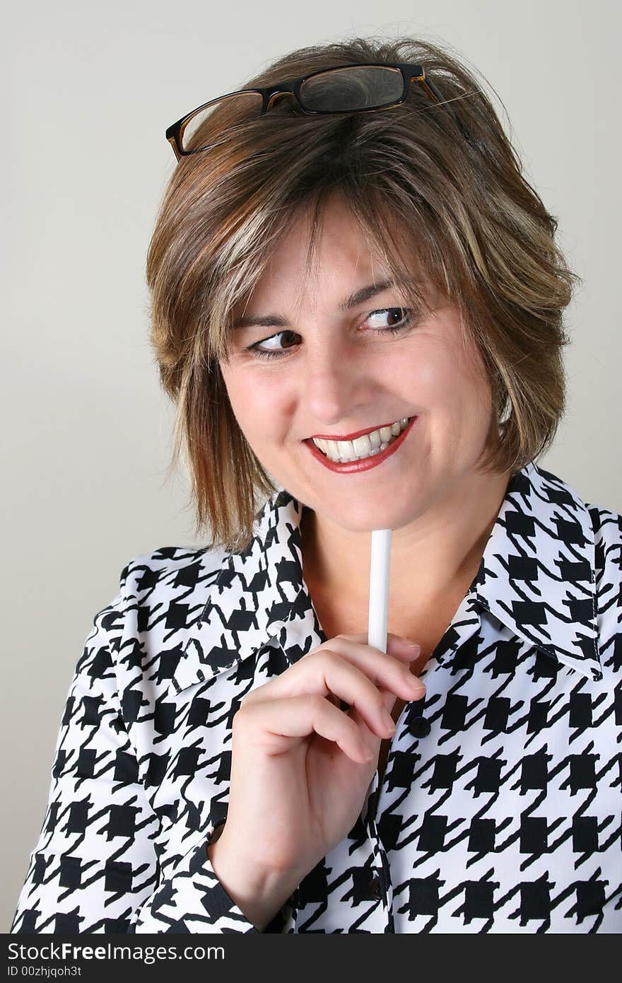 Friendly School Teacher holding white chalk under her chin. Friendly School Teacher holding white chalk under her chin