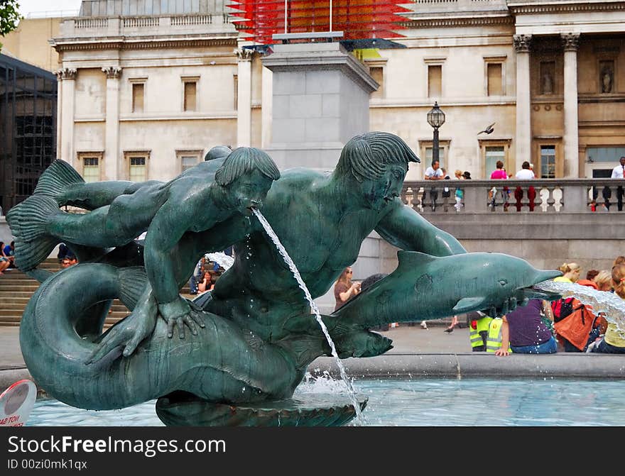 Bronze fountain with a nude young man, a boy and dolphins in Trafalgar Square, London