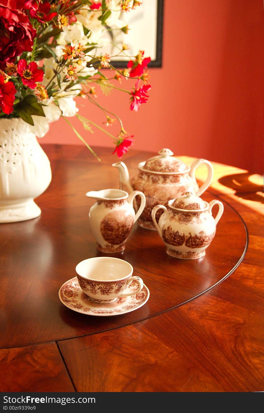 A simple arrangement of teacup and accessories on a dark wood table, perfect for an afternoon tea.