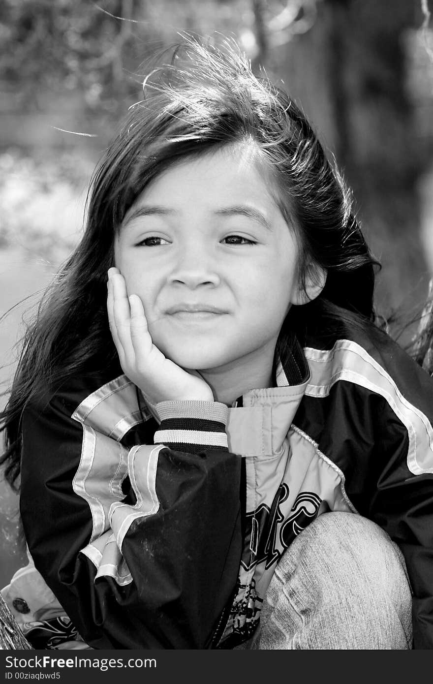 A black & white portrait of a cute young girl outside.