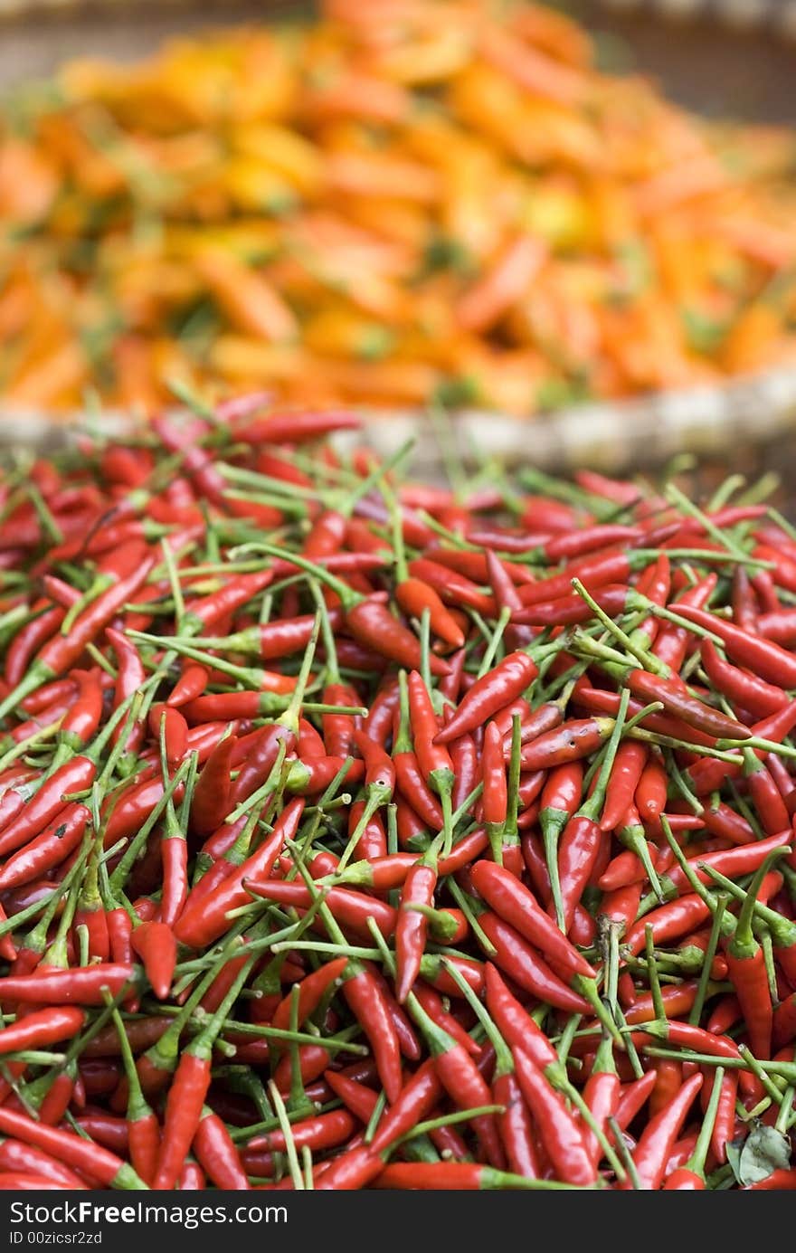 Red chilipepper in the foreground and yellow chilipepper blurred, out of focus in the background. Red chilipepper in the foreground and yellow chilipepper blurred, out of focus in the background