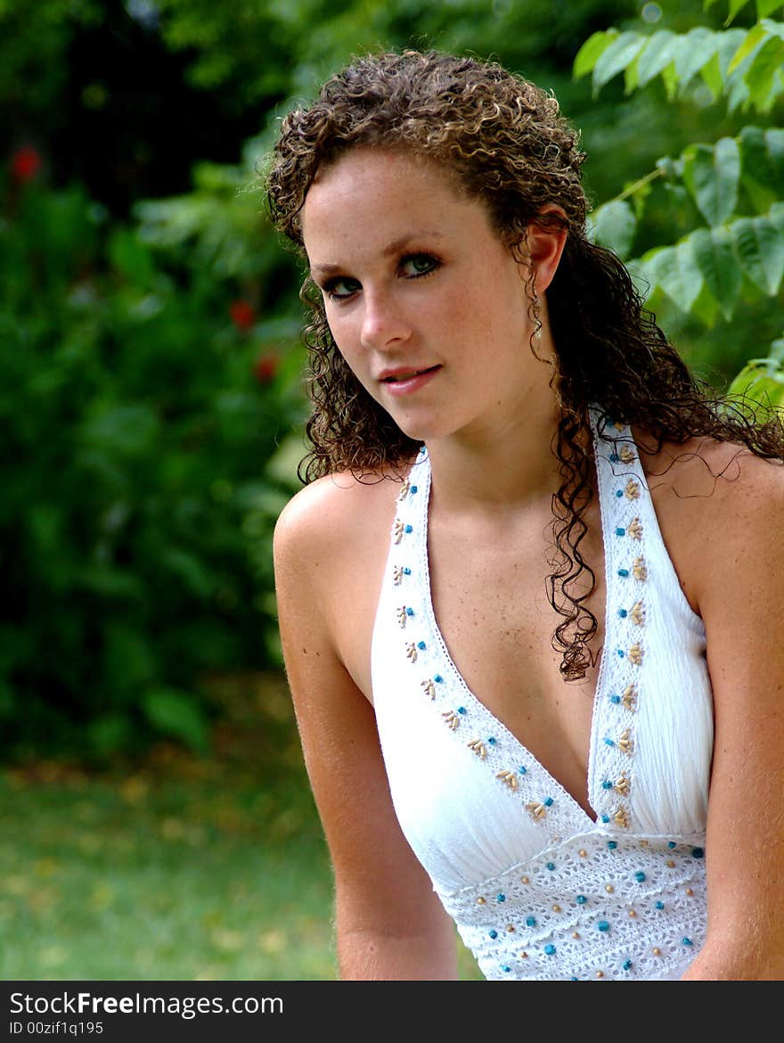 Closeup of young woman in white halter dress with turquoise trim in outdoor location. Closeup of young woman in white halter dress with turquoise trim in outdoor location