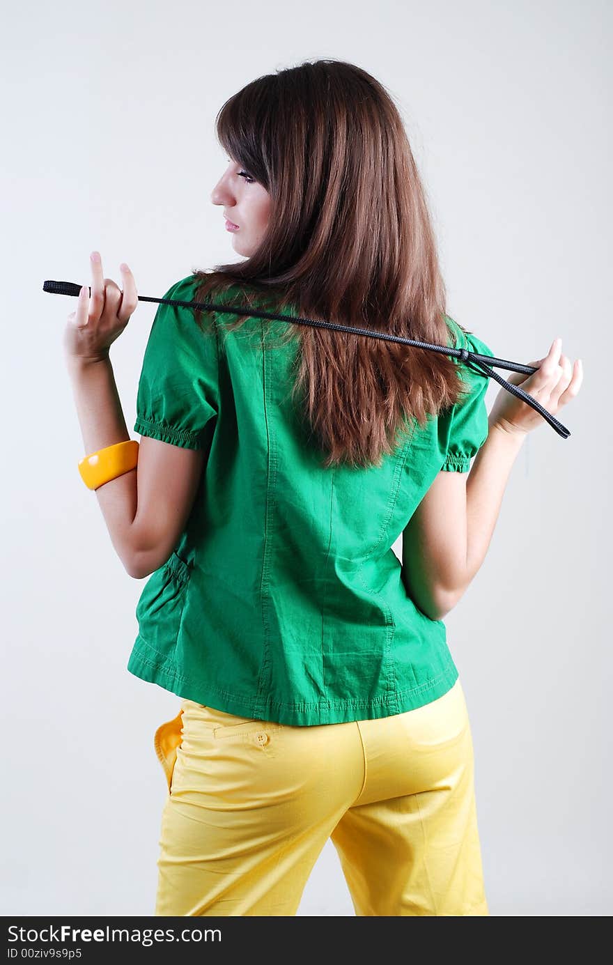 Beautiful girl in a green blouse and yellow shorts with whip on white background. Beautiful girl in a green blouse and yellow shorts with whip on white background