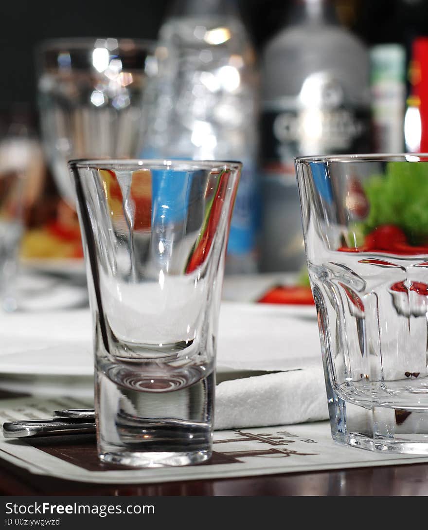 Empty Glasses on Banquet Table with Glare in Bottle Background