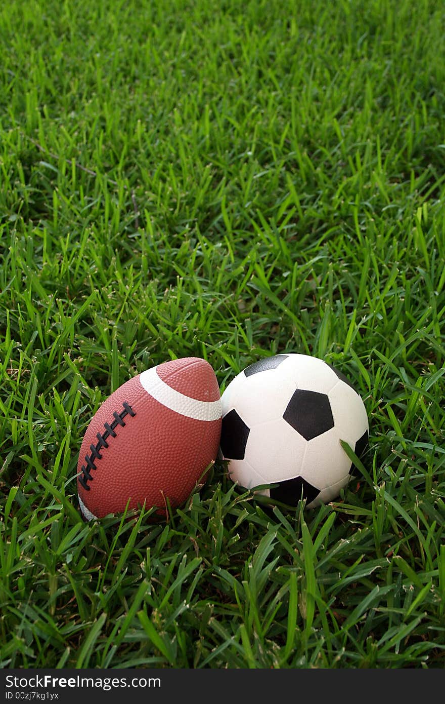 A soccer ball and a football sit next to each other in the grass. A soccer ball and a football sit next to each other in the grass.