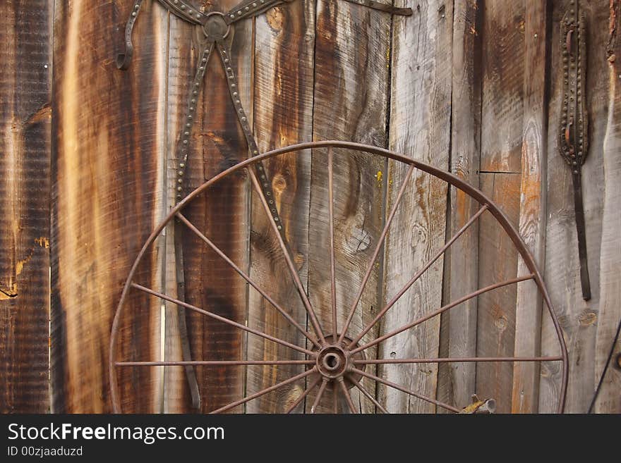 An old horse carriage wheel against a barn wall. An old horse carriage wheel against a barn wall.