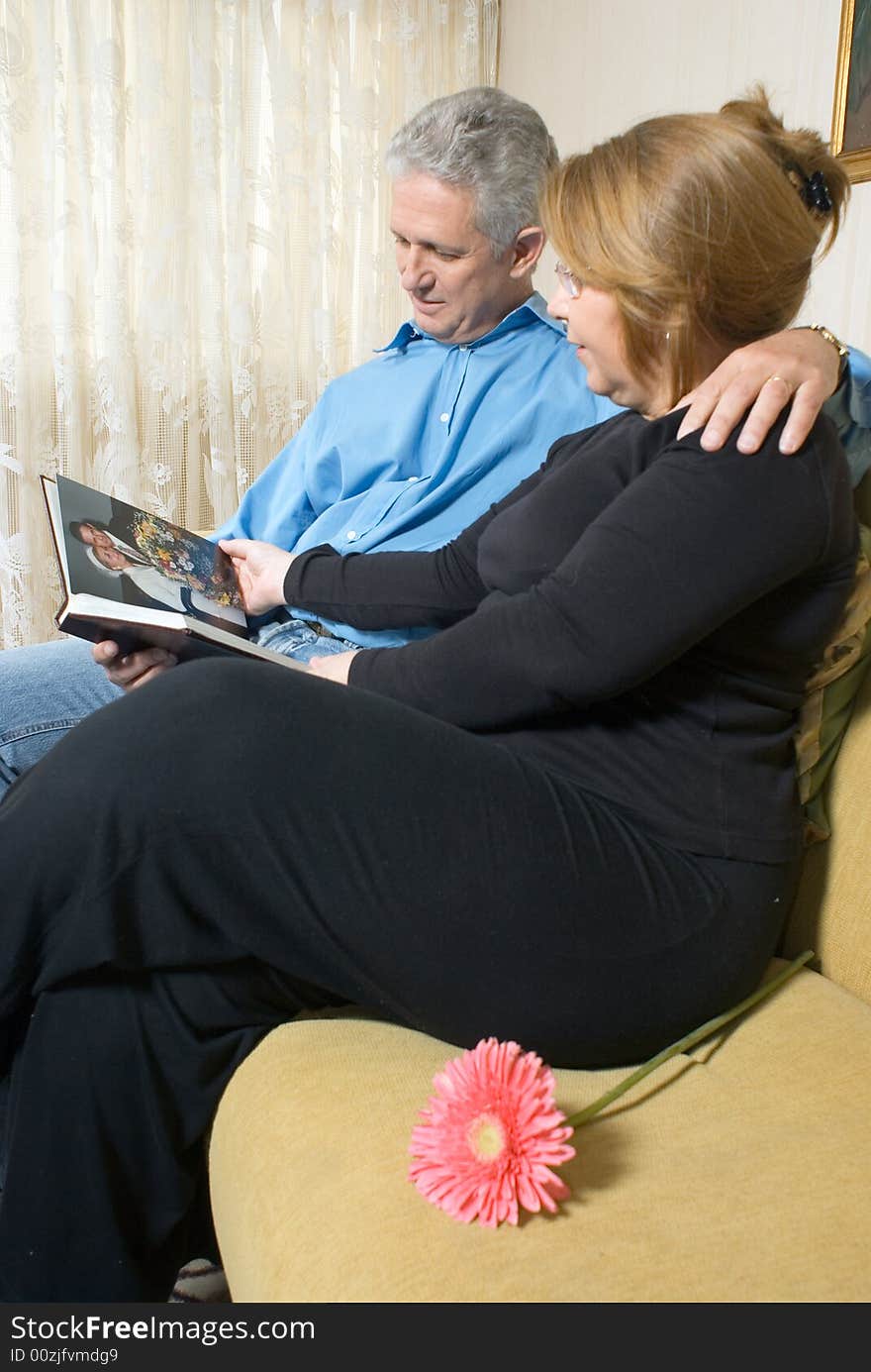 A couple looking at a book of pictures together, reminiscing. - vertically framed. A couple looking at a book of pictures together, reminiscing. - vertically framed