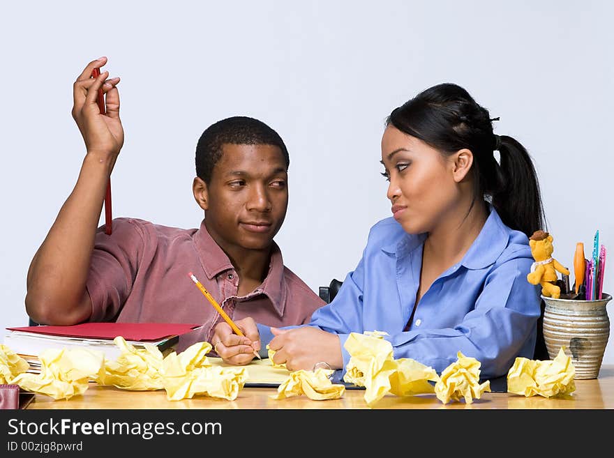 Two students looking at each other smugly as they sit at a desk. Horizontally framed shot. Two students looking at each other smugly as they sit at a desk. Horizontally framed shot.