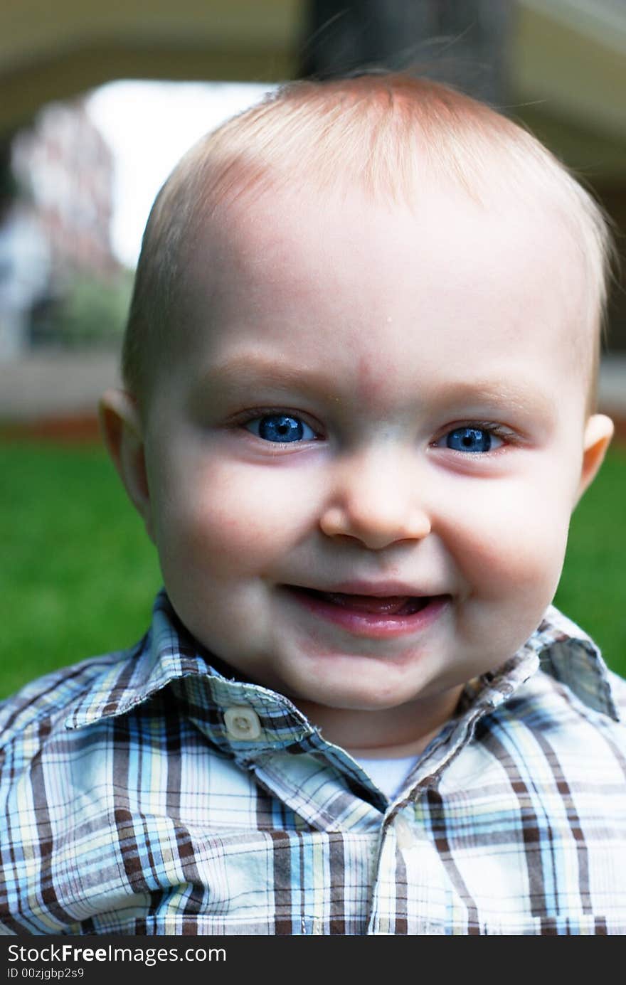 A young child smiles as his picture is being taken at a park. - vertically framed. A young child smiles as his picture is being taken at a park. - vertically framed