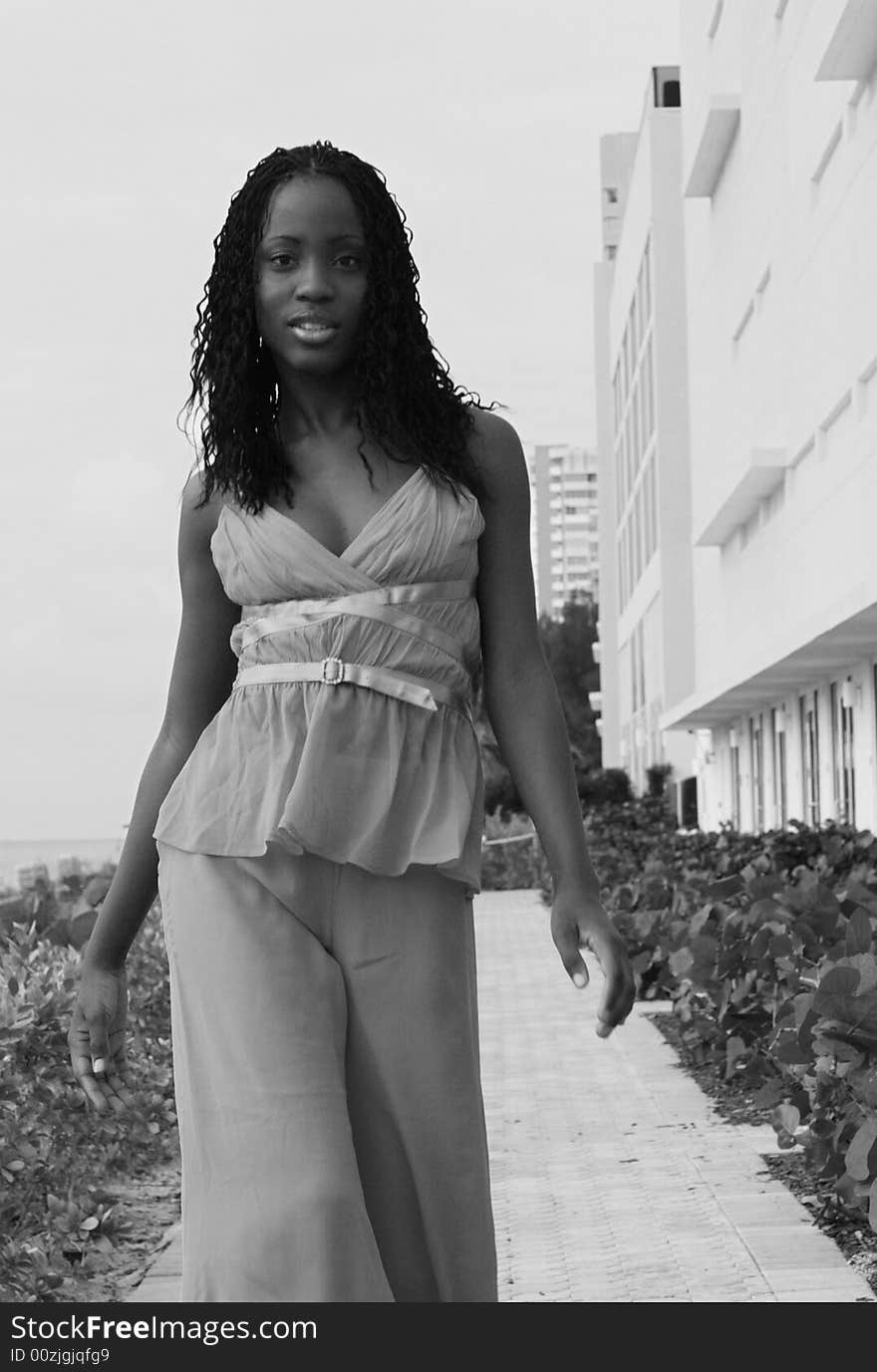 Black and white image of a woman walking along a walkway. Black and white image of a woman walking along a walkway