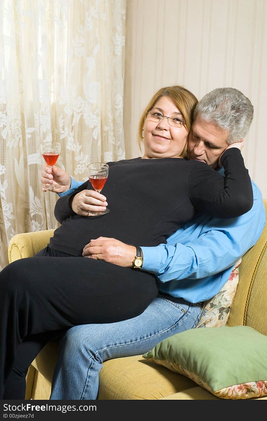 A female sits on a males lap, both drinking out of champagne glasses. - vertically framed. A female sits on a males lap, both drinking out of champagne glasses. - vertically framed