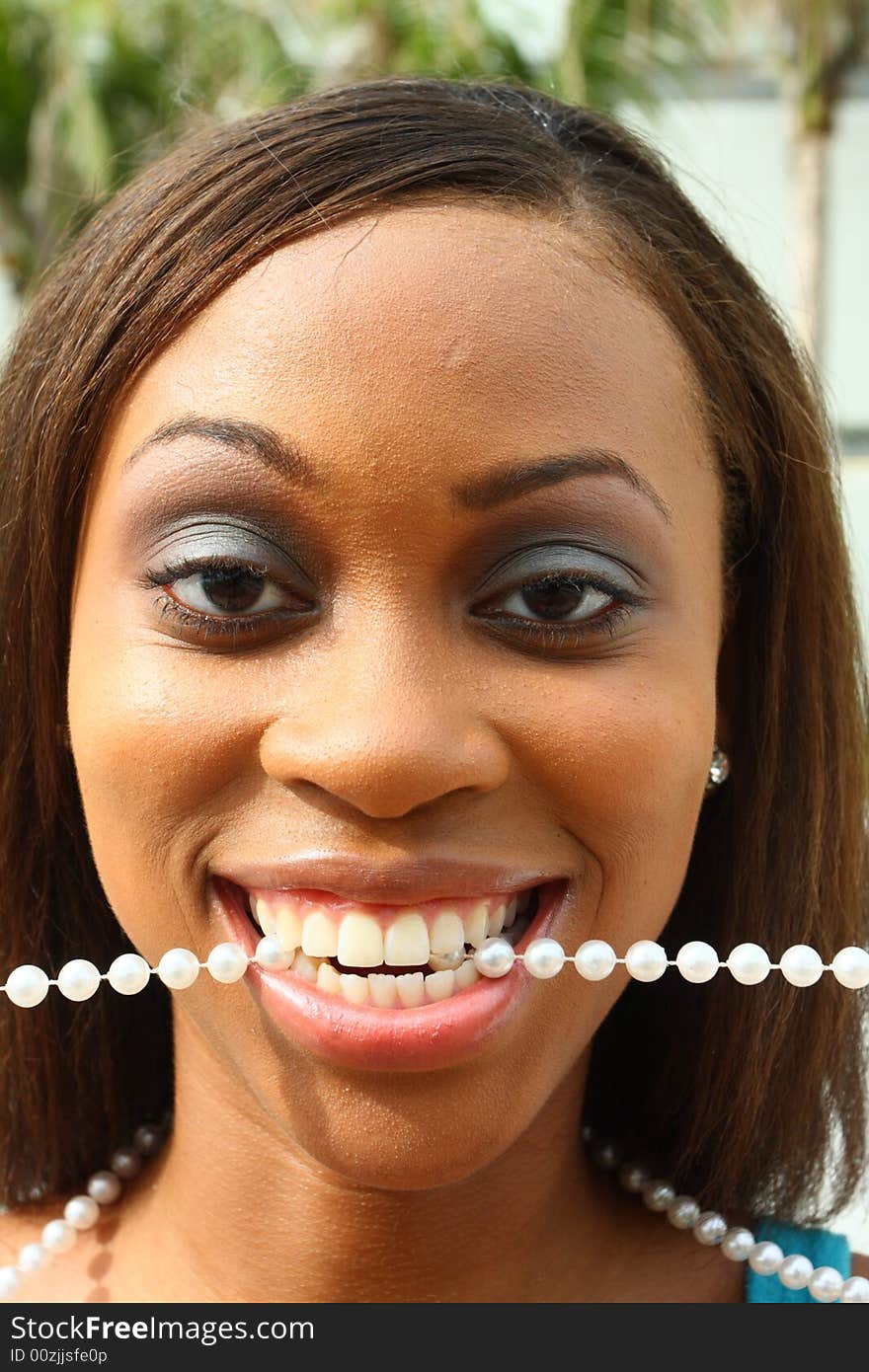 Young woman with a pearl necklace in her mouth. Young woman with a pearl necklace in her mouth.