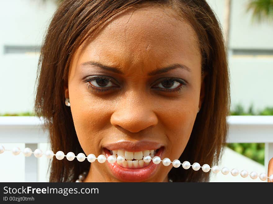 Woman with a string of pearls in her mouth.