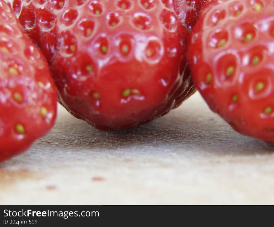 Three shiny strawberries isolated on wooden kitchen board

Focus on the board underneath the strawberries

*RAW format available