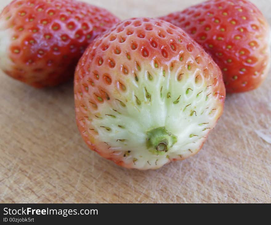 Strawberries, view from behind, close-up image of three strawberries isolated on a wooden board

*RAW format available