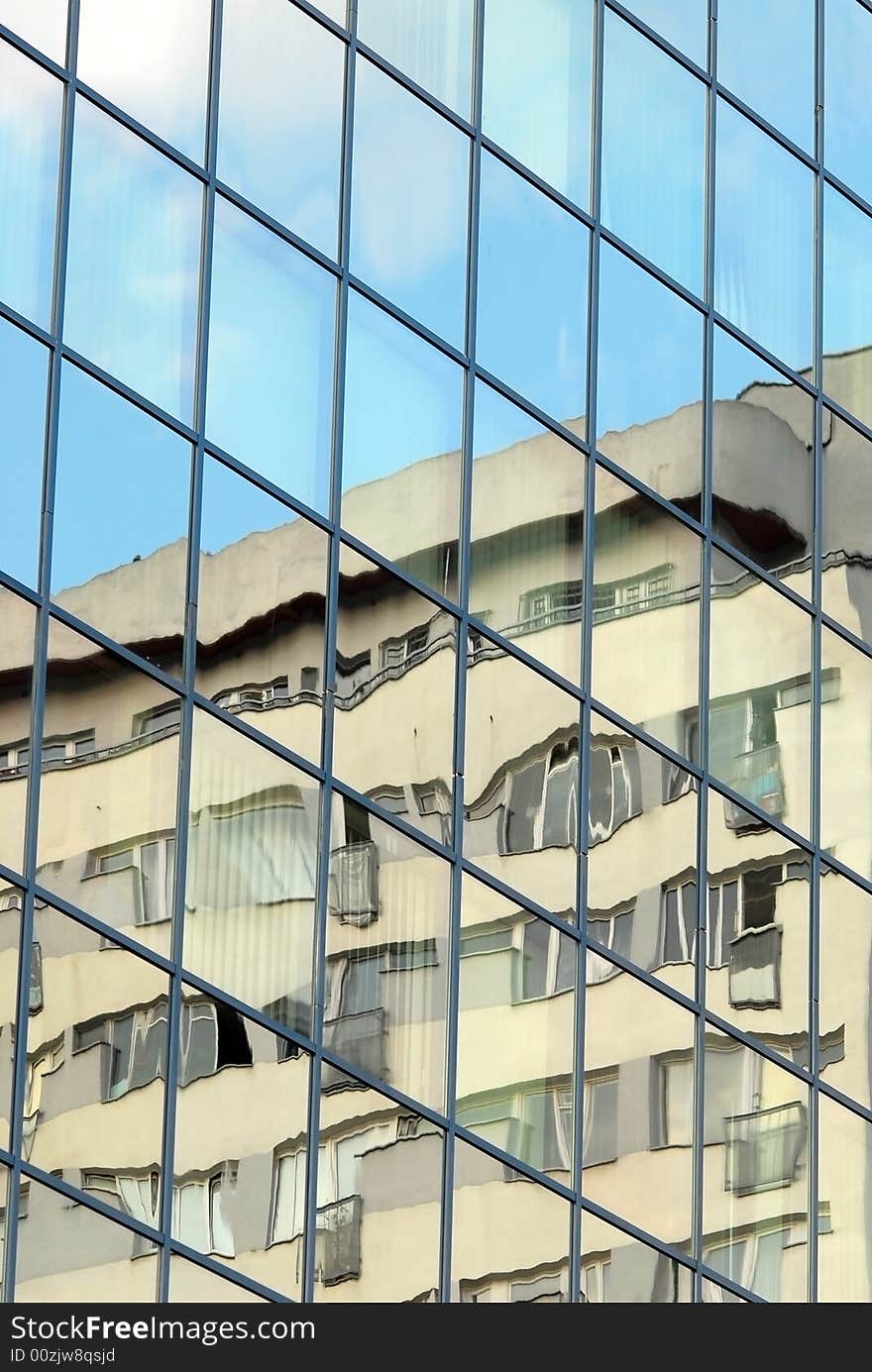 Modern, glass facade of office building. Cloud and sky reflexions plus some glass transparency show a bit interiors with curtains.