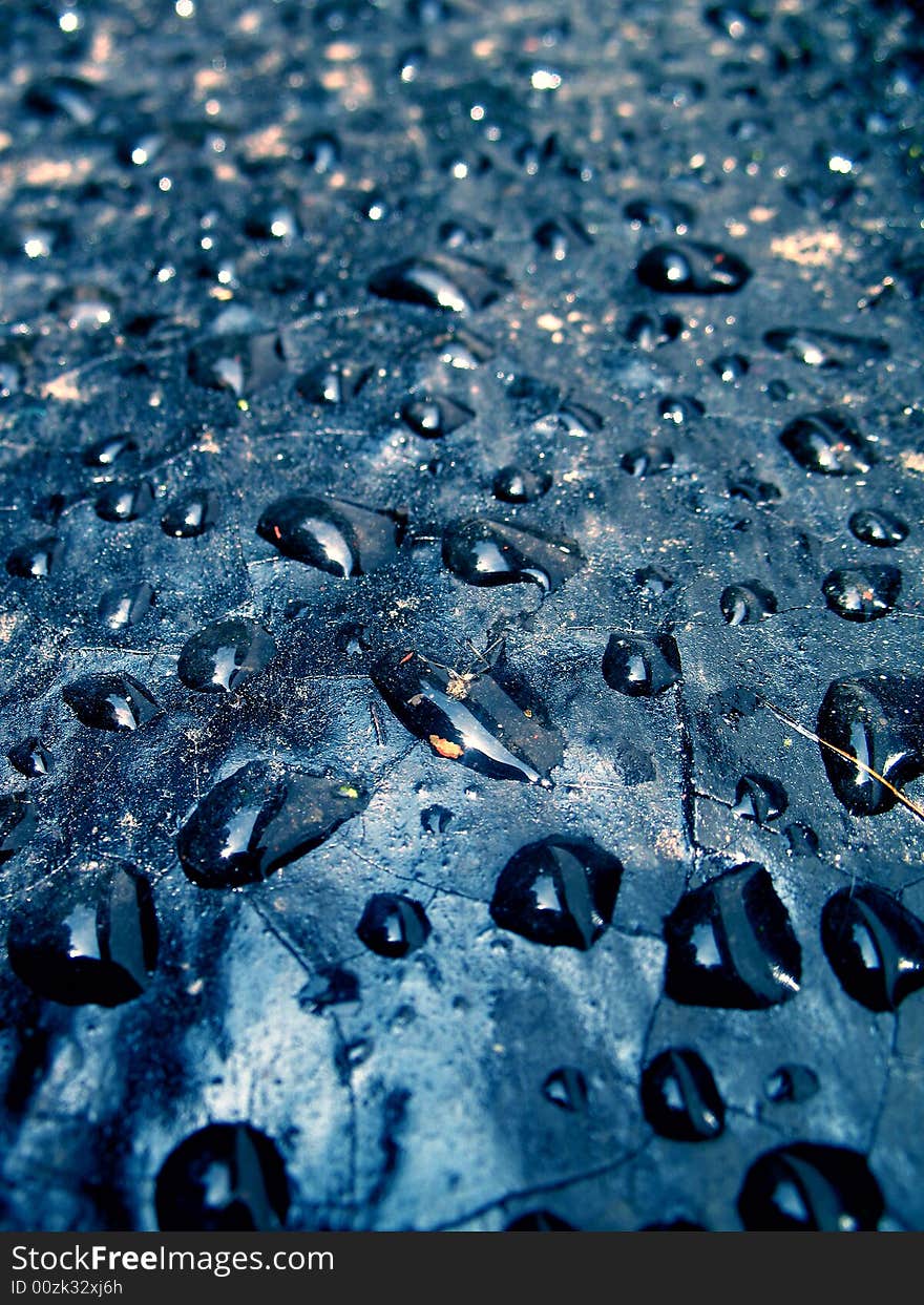 Transparent drops of water on the dark blue cracked background. Transparent drops of water on the dark blue cracked background.