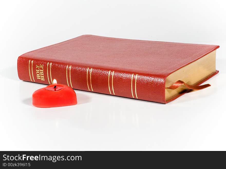 Holy Bible and a red heart-shaped candle. Holy Bible and a red heart-shaped candle