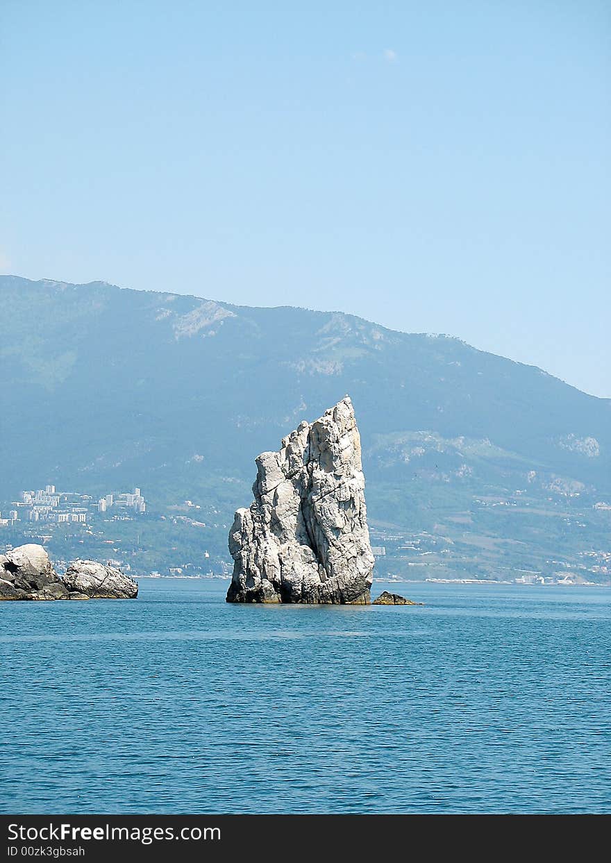 Isolated rock in the blue sea. Isolated rock in the blue sea