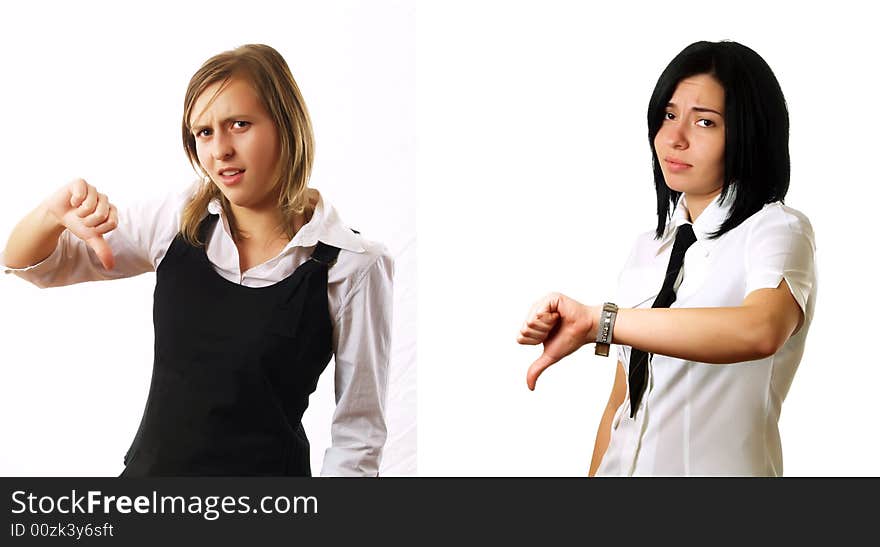 Two elegant businesswomen colleagues are giving the thumbs down and they are sad. They are wearing stylish shirts. Two elegant businesswomen colleagues are giving the thumbs down and they are sad. They are wearing stylish shirts.