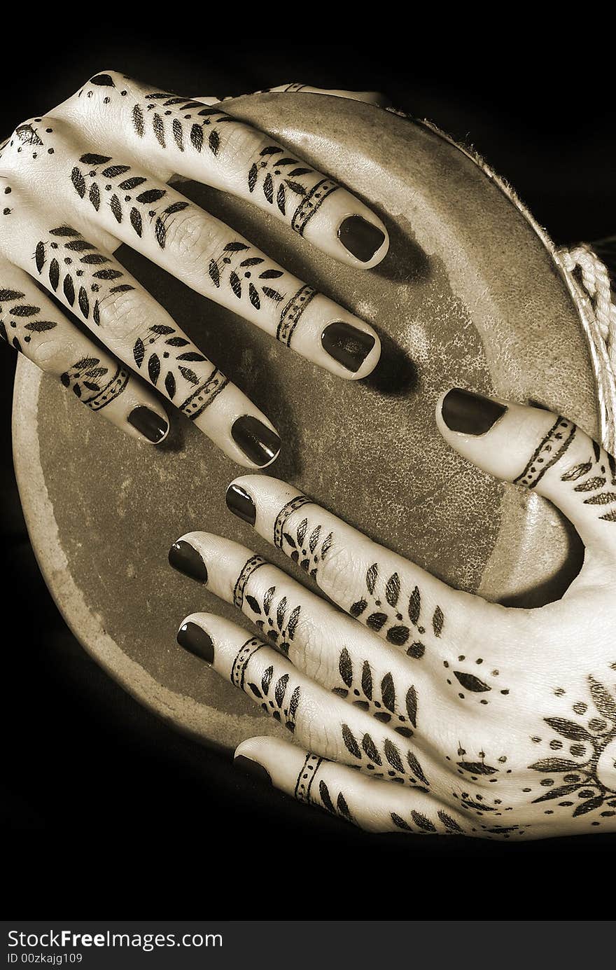 Nice closeup women's hands with oriental tattoo and drum isolated over black