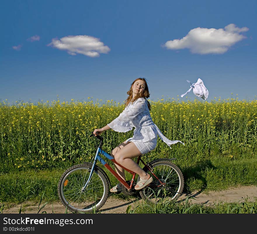 The girl goes on a bicycle and the wind breaks a hat. The girl goes on a bicycle and the wind breaks a hat