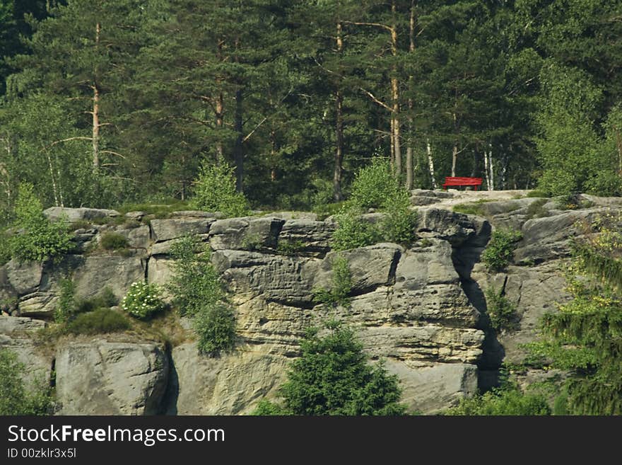 Red park bench on the rock