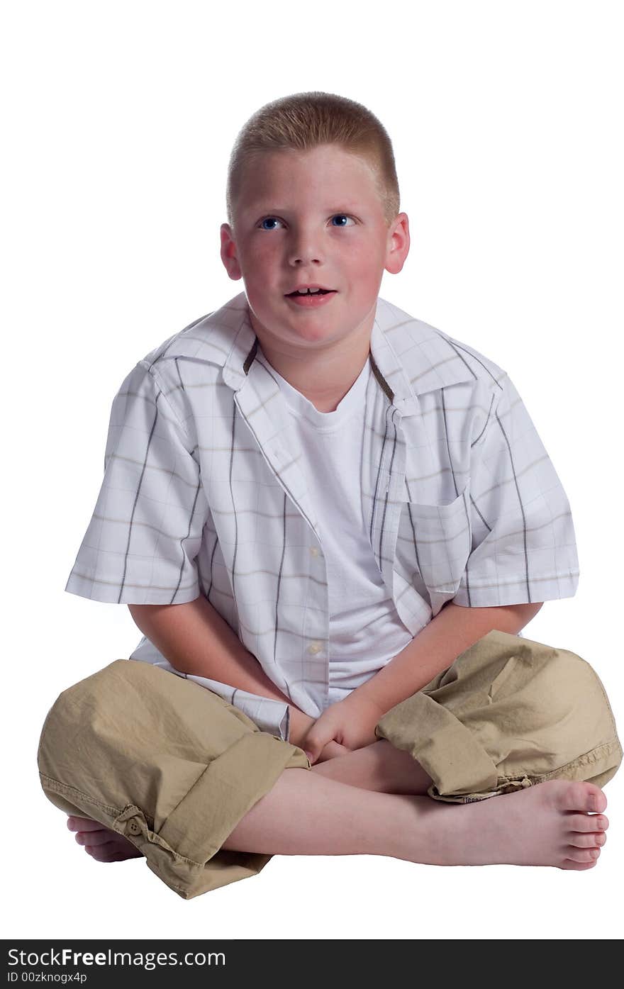 Little boy sitting cross legged on floor with eyes tilted up thinking isolated on white background. Little boy sitting cross legged on floor with eyes tilted up thinking isolated on white background