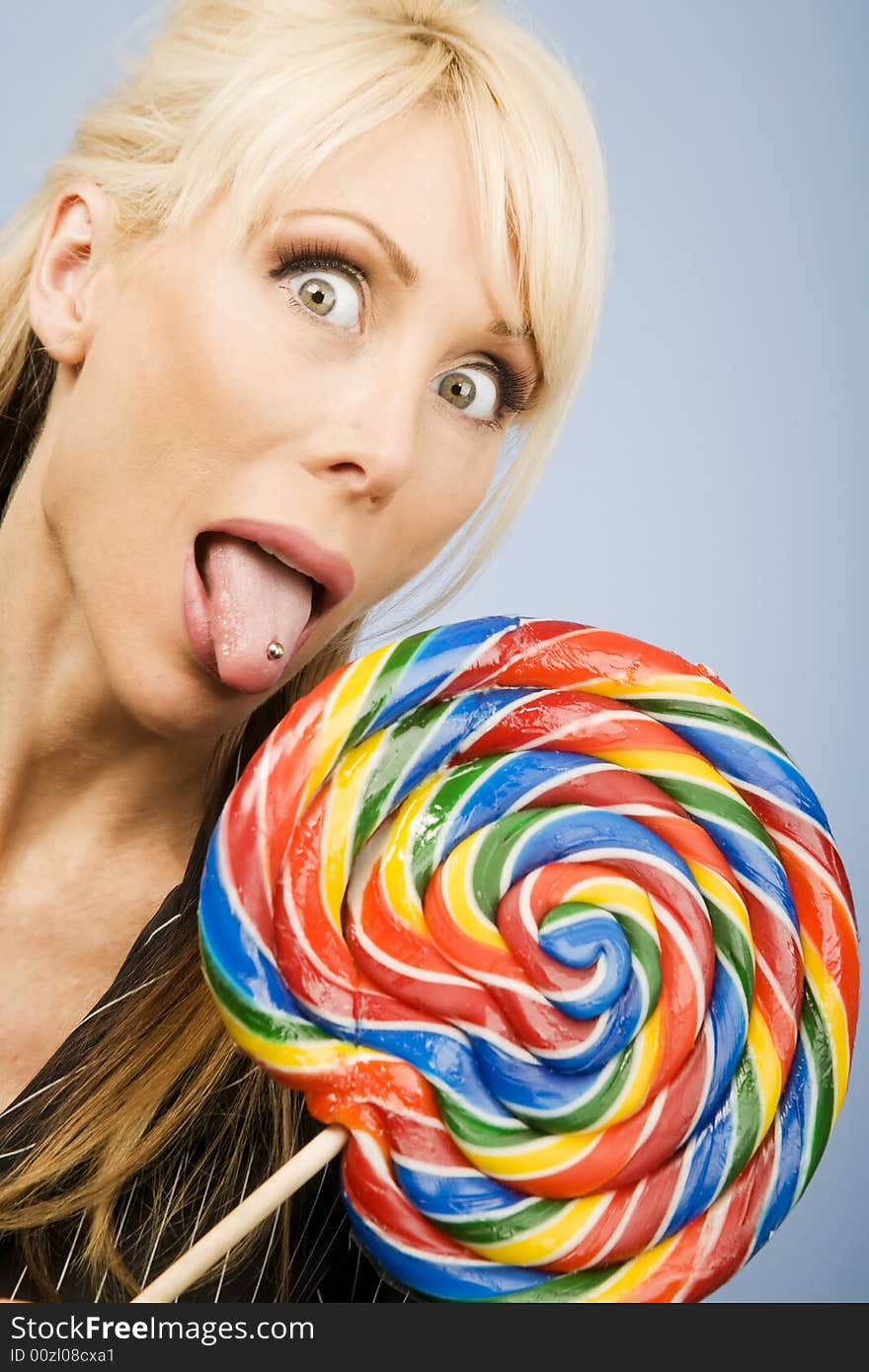 Woman with a pierced tongue licking a big colorful lollipop. Woman with a pierced tongue licking a big colorful lollipop