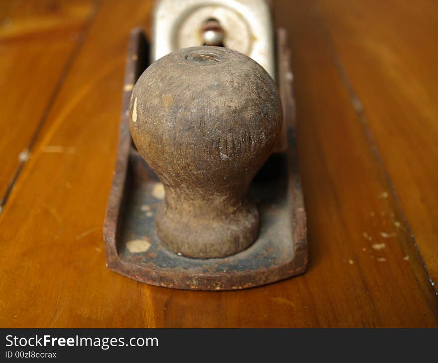 A wooden knob wood plane sits on top a piece of pine. A wooden knob wood plane sits on top a piece of pine.