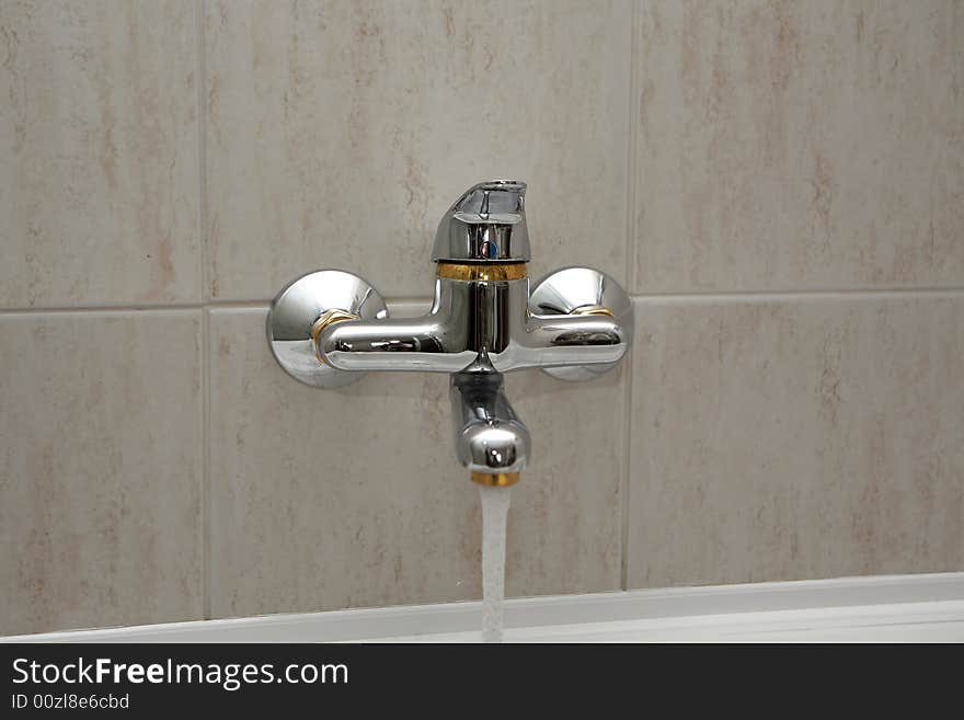 A tap running into washbasin. A tap running into washbasin