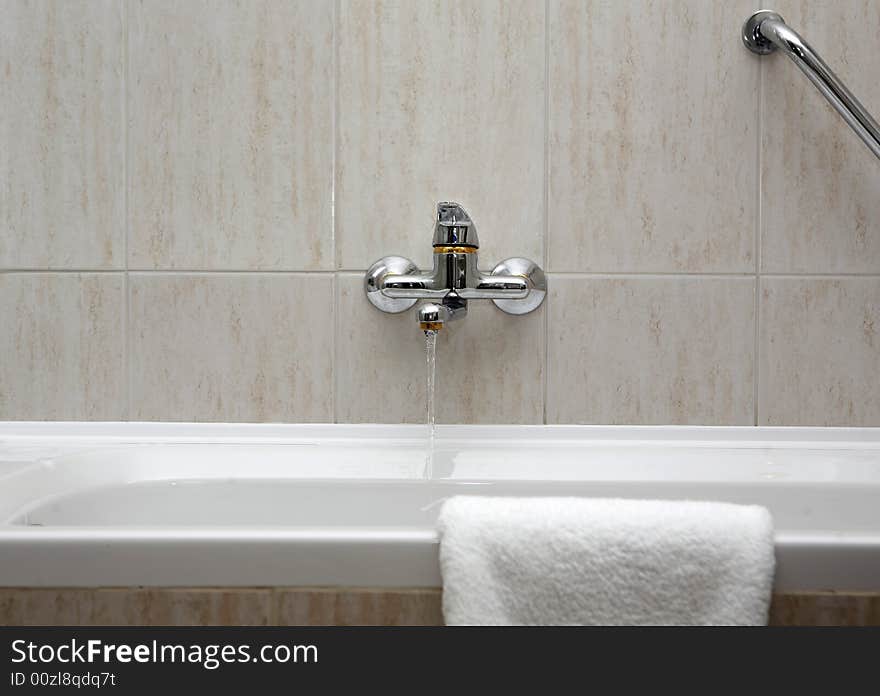 A tap running into washbasin. A tap running into washbasin