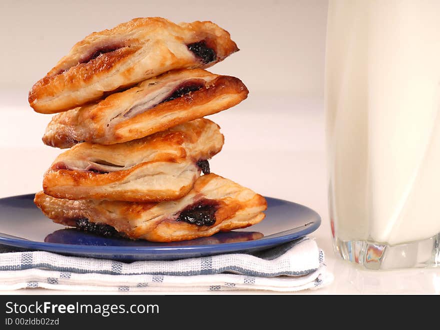 Stack of blueberry turnovers with a glass of milk