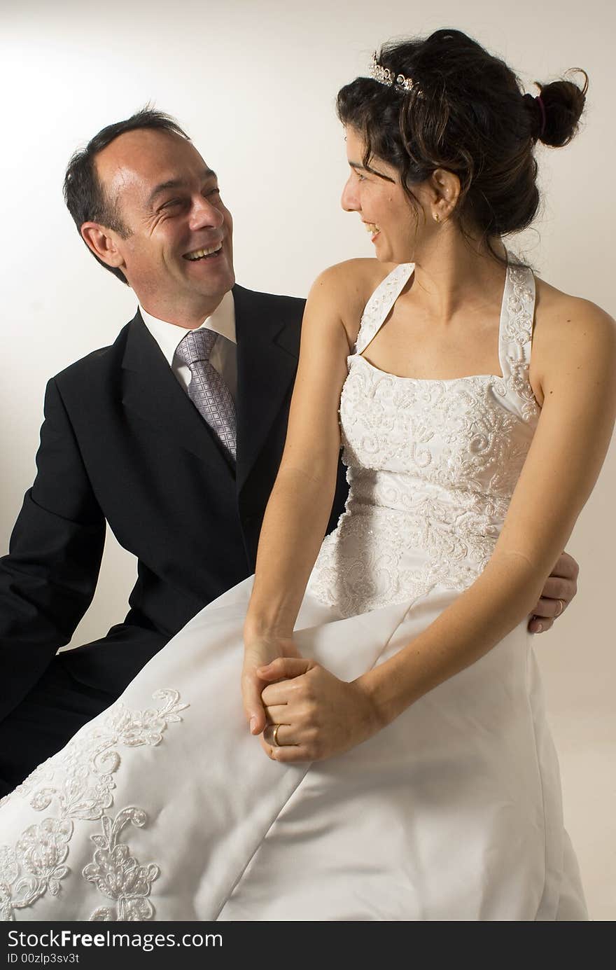 A newly wed couple stare at each other, smiling, while the wife is sitting on the husbands lap. - vertically framed. A newly wed couple stare at each other, smiling, while the wife is sitting on the husbands lap. - vertically framed