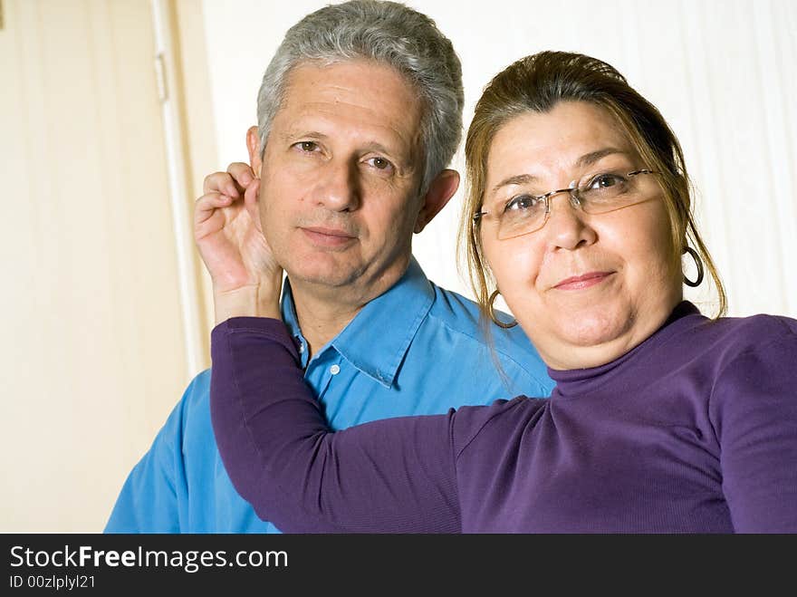 A wife holding onto her husbands ear, they both stare into the camera. - horizontally framed. A wife holding onto her husbands ear, they both stare into the camera. - horizontally framed