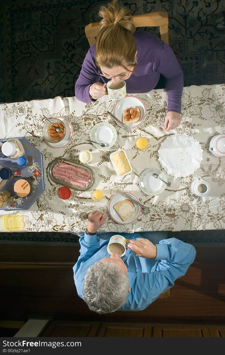 A couple eating a meal at their table.  - vertically framed. A couple eating a meal at their table.  - vertically framed