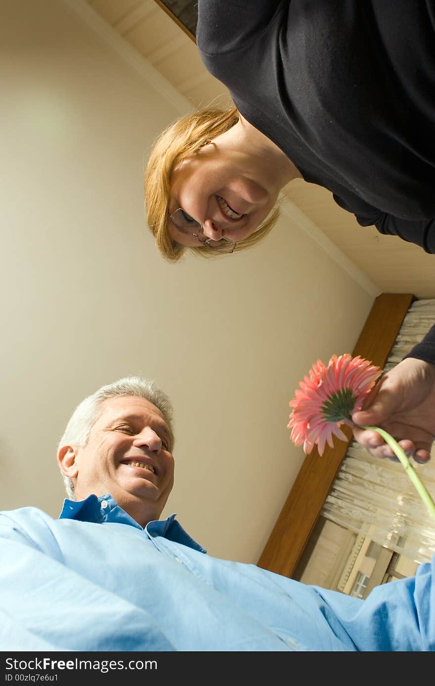 Abstract shot of an older couple smiling and laughing and enjoying each other's company. They are holding a flower between them, romantically.  Vertically framed shot. Abstract shot of an older couple smiling and laughing and enjoying each other's company. They are holding a flower between them, romantically.  Vertically framed shot.