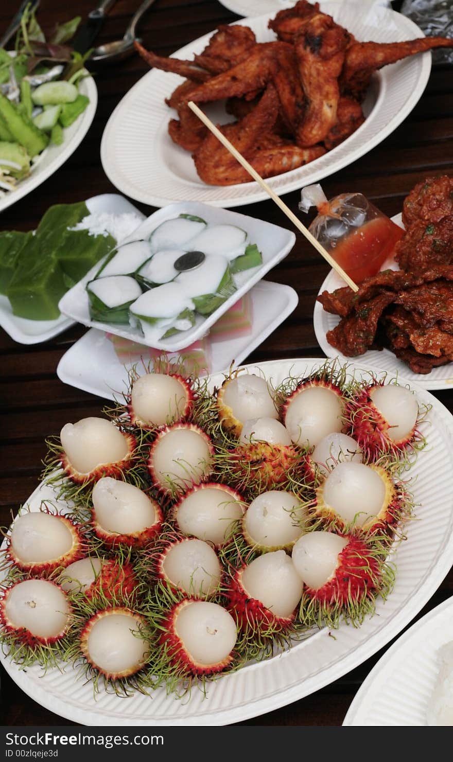 Table of Thai food including rumbutan tropical fruit.