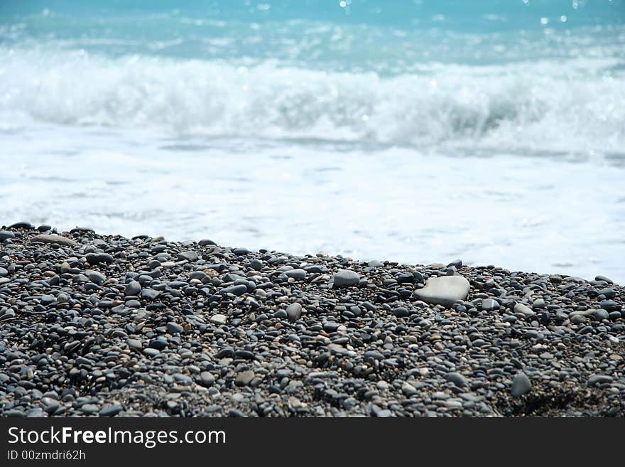 Stones and crushing wave blurry in background in Nice beach, France. Stones and crushing wave blurry in background in Nice beach, France